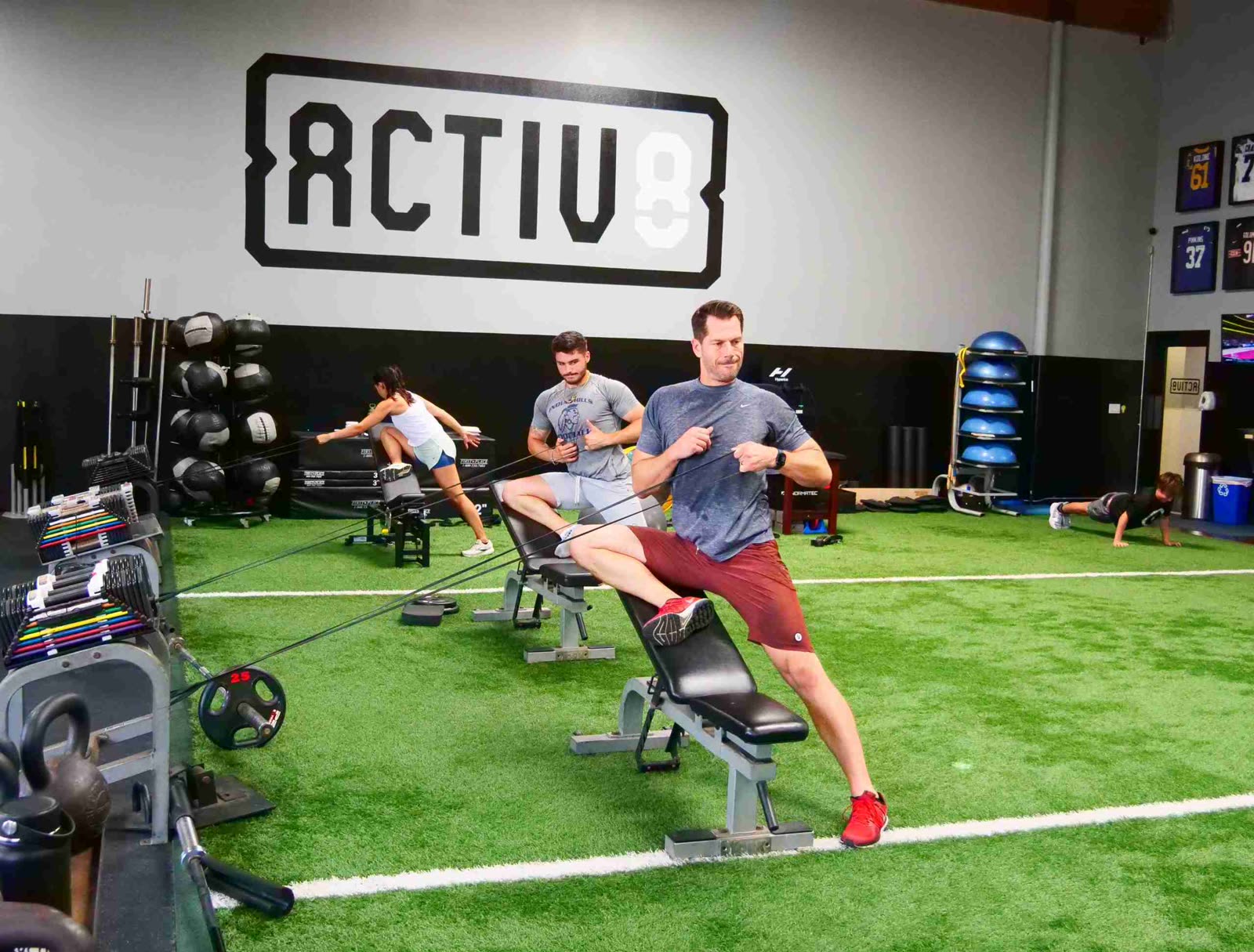 Adult athletes training with resistance cables, benches and plyo boxes at Activ8 in Carlsbad
