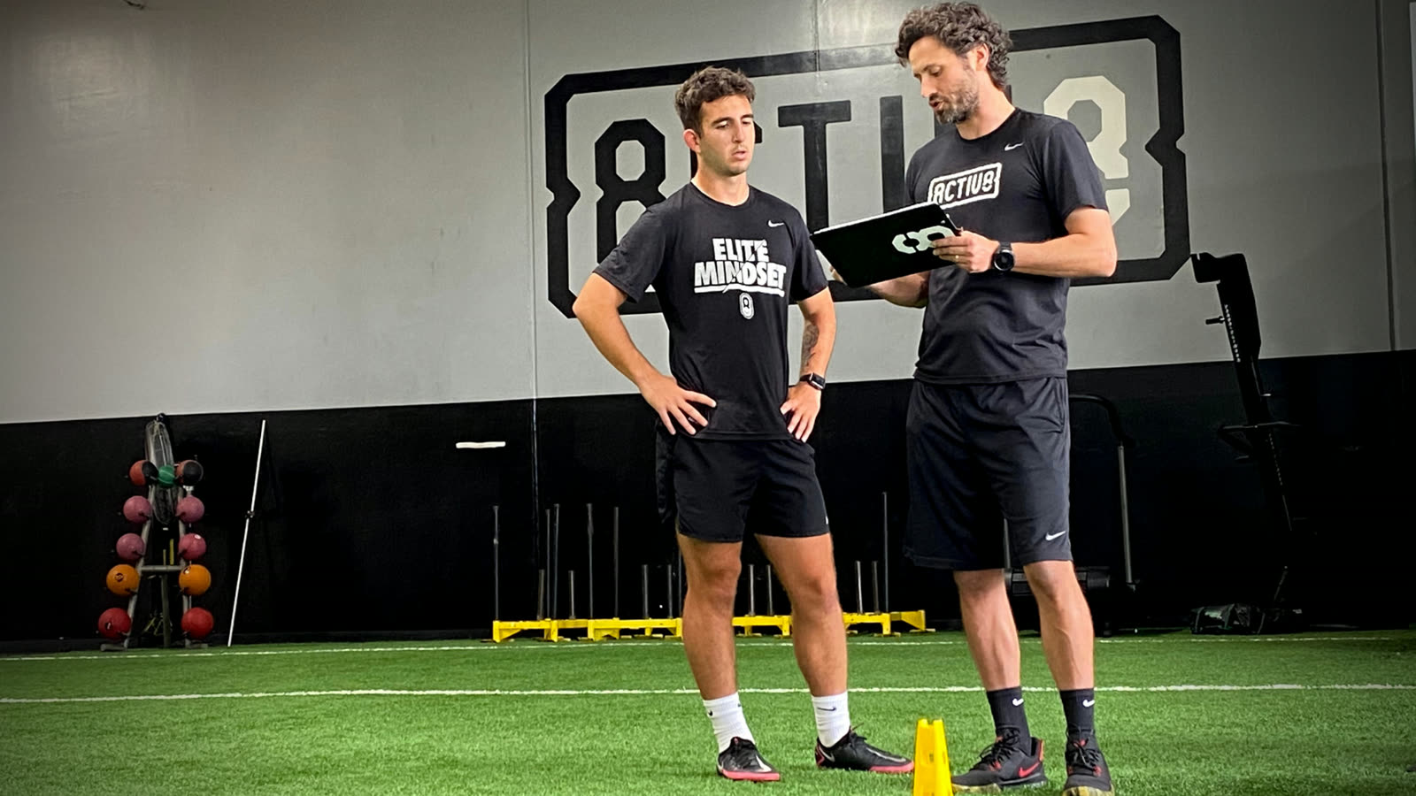 Activ8 coach reviewing a performance plan on a tablet with an athlete at the Carlsbad facility