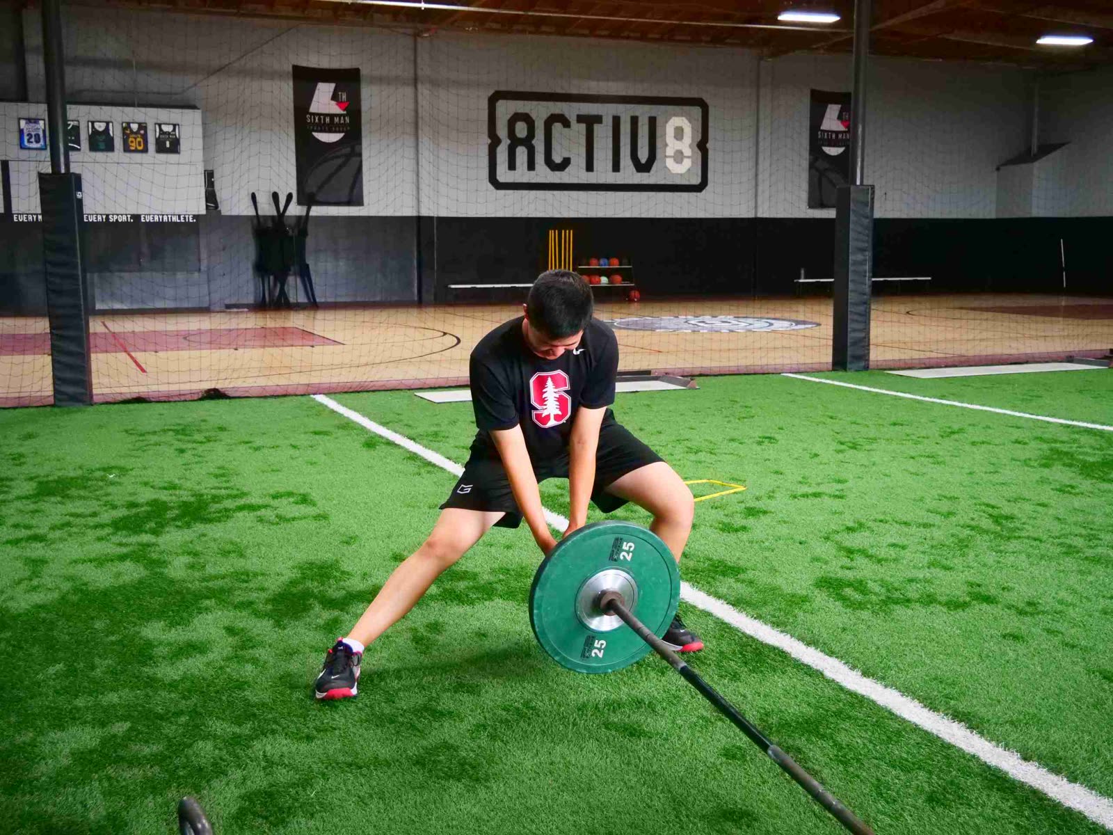 High school athlete doing a landmine barbell drill on the Activ8 turf in Carlsbad